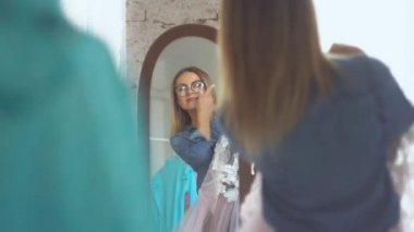 Dikiş atölyesinde güzel bir terzi. Aynanın önündeki elbiseye hayran.