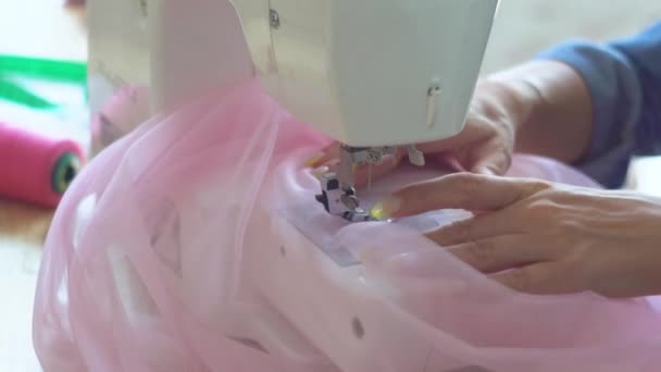 Hermosa costurera rubia en el estudio de costura cose tela en la máquina de coser. Vista de cerca de las manos y la aguja de coser — Vídeos de Stock