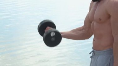 Genç sakallı atletik vücut geliştirici dışarıda spor yapıyor. Halterci. Vücut geliştirme.