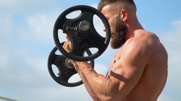 Jovem fisiculturista atlético barbudo joga esportes ao ar livre. Halterofilista. Musculação . — Vídeo de Stock