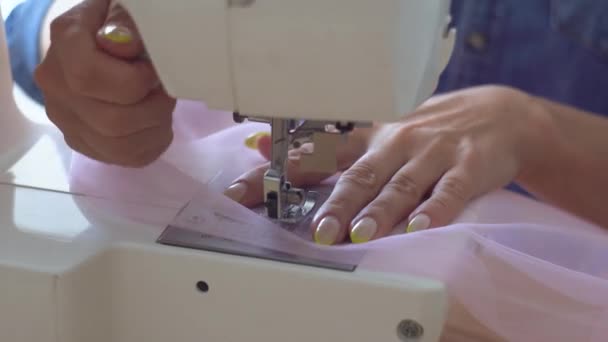 Beautiful seamstress blonde in sewing studio sews fabric on sewing machine. Closeup view of hands and sewing needle — ストック動画