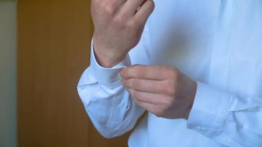 Giyinik adam. İş adamı gömleğini ilikliyor.