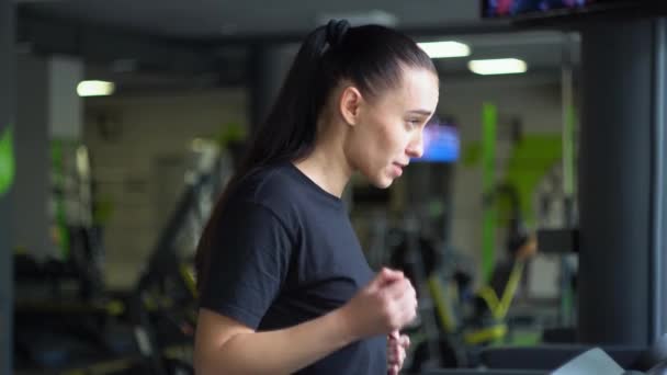 체육관에서 러닝 머신 위를 달리는 매력적 인 여자 — 비디오