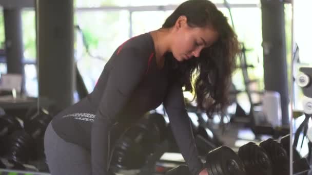 Junge Fitness-Frau trainiert im Fitnessstudio mit Kurzhanteln — Stockvideo