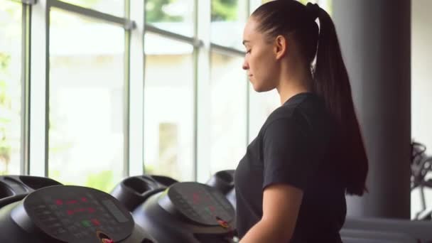 Chica atractiva corriendo en la cinta de correr en el gimnasio — Vídeo de stock