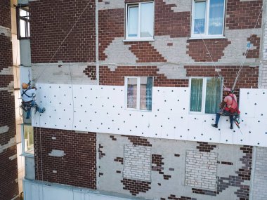 Two industrial climbers makes warming at home. Workers warming the facade of a building clipart