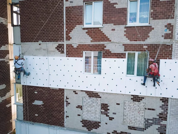 Two industrial climbers makes warming at home. Workers warming the facade of a building — Stock Photo, Image