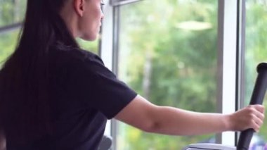 Spor salonunda eliptik çapraz antrenör eğitimi almadan önce portre fitness kadını ısınıyor.