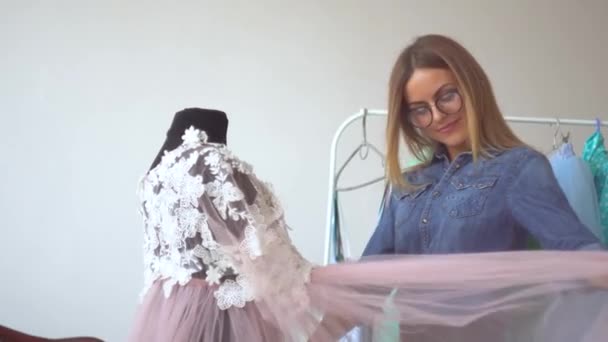 Linda costureira loira no estúdio de costura corrige vestido no manequim — Vídeo de Stock