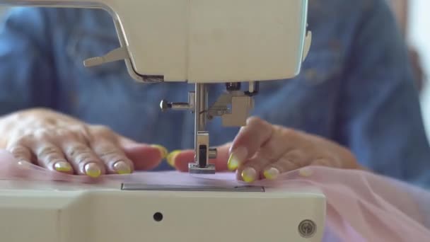 Hermosa costurera rubia en el estudio de costura cose tela en la máquina de coser. Vista de cerca de las manos y la aguja de coser — Vídeos de Stock