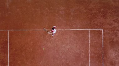 Genç tenisçi tenis kortunda raket topuna vuruyor.