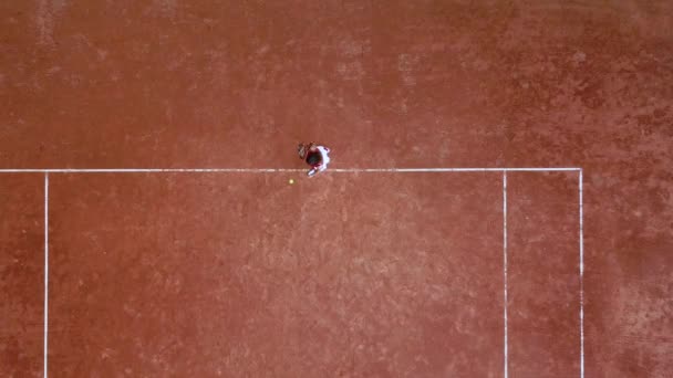 Joven jugador de tenis golpea una pelota de raqueta en una cancha de tenis — Vídeo de stock