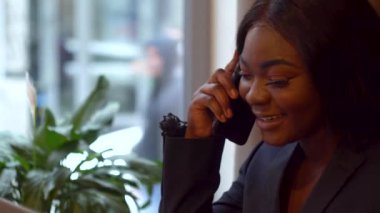 Afrikalı Amerikalı iş kadını iş ortağıyla telefonda konuşuyor.