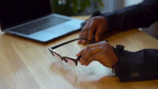 Африканская американская бизнесвумен надевает очки в бизнес-центре. Девушка работает с ноутбуком — стоковое видео