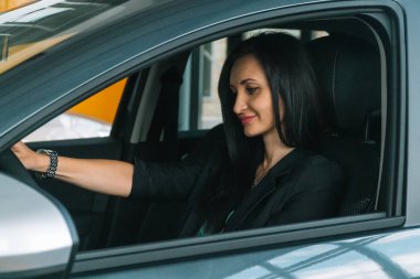 Woman wearing smart casual wear sits in car interior
