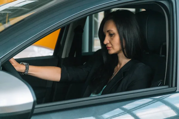 Mujer usando ropa casual inteligente se sienta en el interior del coche — Foto de Stock