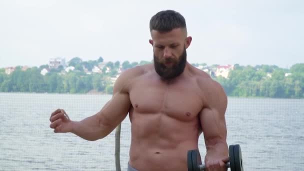 Jeune bodybuilder athlétique barbu fait du sport à l'extérieur. Haltérophilie. Carrosserie — Video