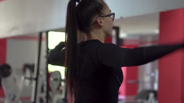 Hermosa chica en gafas en el club deportivo hace diferentes tipos de ejercicios — Vídeos de Stock