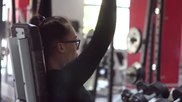Красивая девушка в очках в спортивном клубе делает различные упражнения — стоковое видео