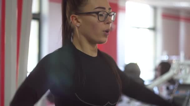 Spor kulübünde gözlüklü güzel bir kız farklı egzersizler yapıyor. — Stok video