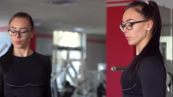 Young fitness woman exercising in the gym with blue dumbbells. Beautiful girl in glasses at the sports club does different kind of exercises on the simulators — Stock Video