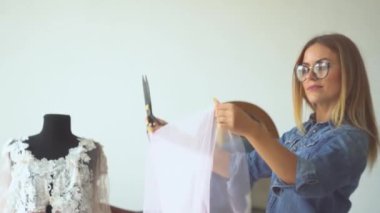 Dikiş atölyesindeki güzel terzi sarışın kuklanın yanında kumaşla çalışıyor. Kadın kıyafetleri modelleme süreci.