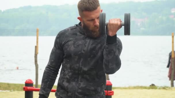 Jovem fisiculturista atlético barbudo joga esportes ao ar livre. Halterofilista. Musculação — Vídeo de Stock