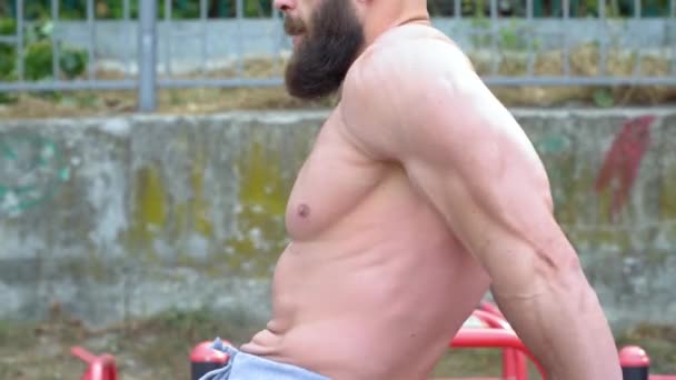 Bodybuilder demonstreert spieren. Jonge bebaarde atletische bodybuilder speelt buiten sporten. — Stockvideo