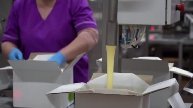 Yağı paketleme ya da kutuya yayma işlemi. Makine yağı kutuya koyar, fabrika işçisi de kutuyu.