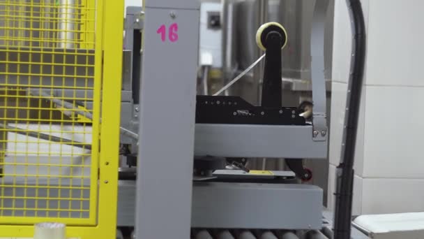Automatic adhesive taping of a cardboard box on a conveyor belt — Stockvideo