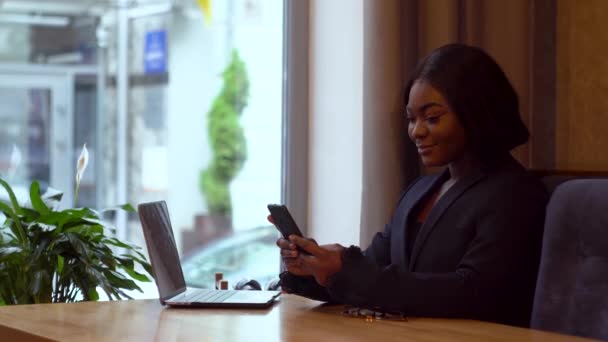 African american businesswoman working with laptopand smartphone — Stockvideo