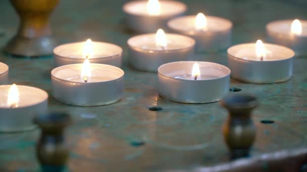 Las velas se encienden de cerca en la iglesia. Velas encendidas frente al altar — Vídeo de stock