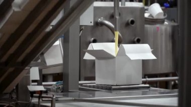 Yağı kutulara koyma süreci. Paketleme makinesinin yakın görüntüsü. Makine yağı kutuya koyar, fabrika işçisi de kutuyu.