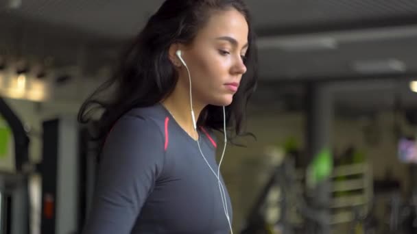 Chica atractiva corriendo en la cinta de correr en el gimnasio — Vídeo de stock