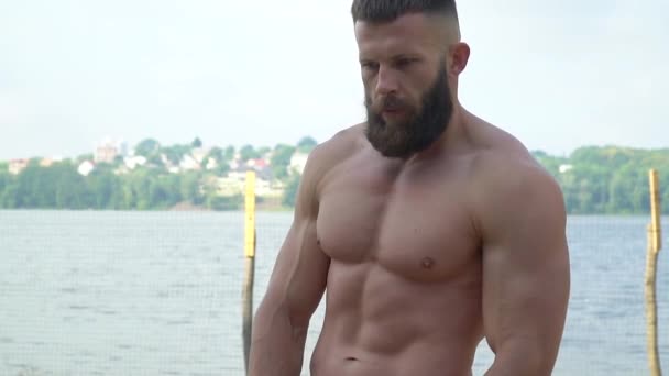 Bodybuilder demonstrates muscles. Young bearded athletic bodybuilder plays sports outdoors — Stock Video