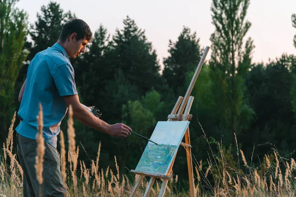 남성 미술가는 자연 풍경의 일몰 풍경을 그리고 있습니다. 한 남자가 그림을 그리다 — 스톡 사진