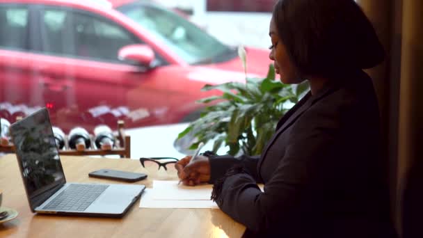 African american businesswoman working with laptop and papers — Stock Video