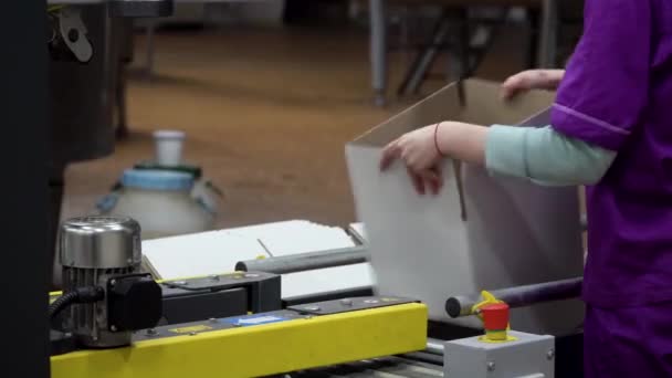 Bir fabrika işçisi yeni kutular hazırlar ve onları taşıyıcıya koyar. — Stok video