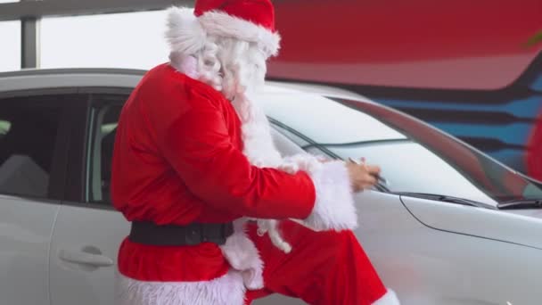 Papai Noel em uma concessionária de carros escreve algo na lista — Vídeo de Stock