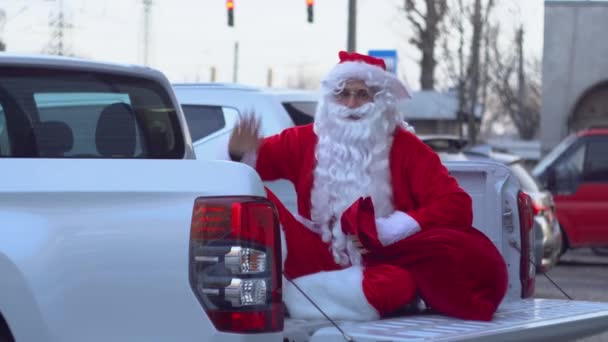 Der Weihnachtsmann sitzt im Fond eines Pickups. Weihnachtsmann im Autohaus — Stockvideo