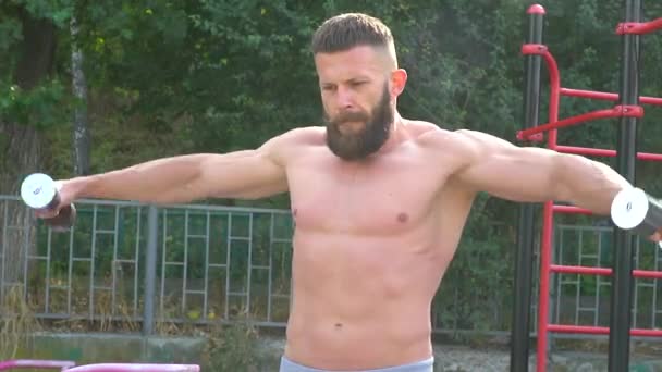 Bodybuilder επιδεικνύει μυς. Νέοι γενειοφόροι αθλητικός bodybuilder παίζει σπορ — Αρχείο Βίντεο