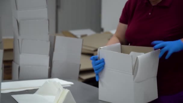 Una trabajadora de fábrica pone papel en medio de una caja vacía y lo pone en un transportador — Vídeos de Stock