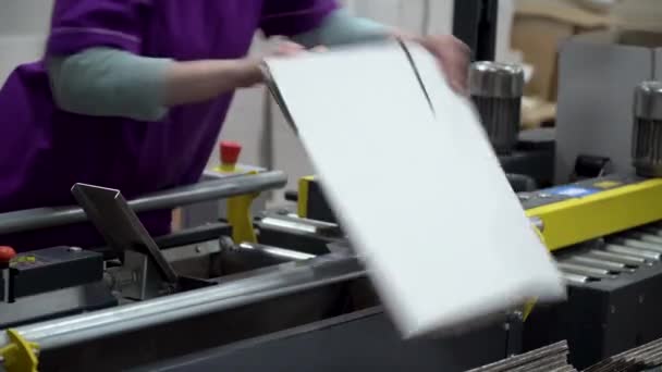 Een vrouwelijke fabrieksarbeider legt nieuwe blanco witte dozen op een transportband. — Stockvideo