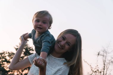 Anne ve küçük oğlu parkta eğleniyorlar. Doğal ortamda aile eğlencesi.