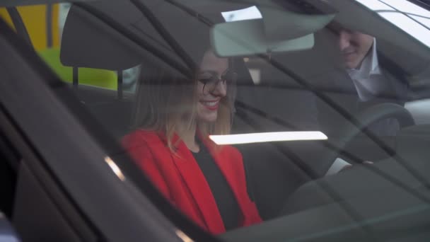 汽车经销店的顾问把一辆汽车送给一位穿红色衣服的妇女 — 图库视频影像