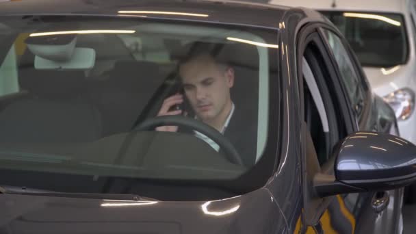 Uomo d'affari seduto al volante di una macchina presso la concessionaria auto — Video Stock