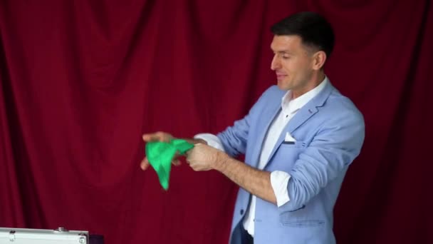 Magician in a suit shows a trick with shawl on a vinous background — Stok video