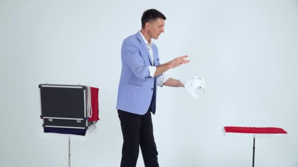 Zauberer im Anzug zeigt einen Trick mit Lampe auf weißem Hintergrund — Stockvideo