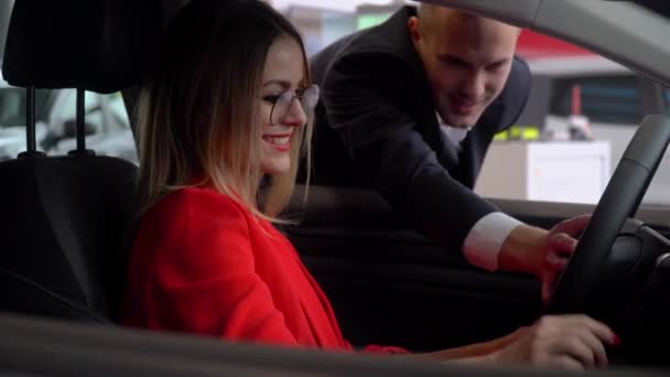 Consultor en un concesionario de automóviles presenta un coche a una mujer de negocios — Vídeos de Stock