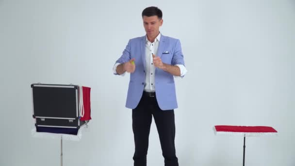 Magiker i kostym visar ett trick med blomma på en vit bakgrund — Stockvideo